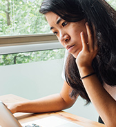 A student looks at their laptop screen, frowning